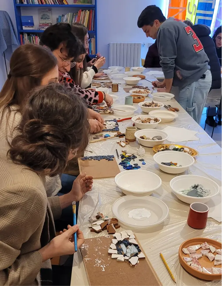 Giovani partecipanti realizzano mosaici con materiali di recupero durante un laboratorio artistico del progetto ECOSCENA