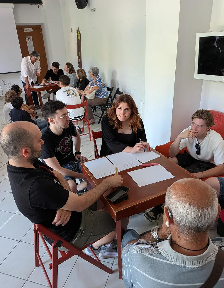 Giovani e adulti si confrontano in piccoli gruppi durante un incontro di dialogo intergenerazionale del progetto Giovani Cittadini Attivi