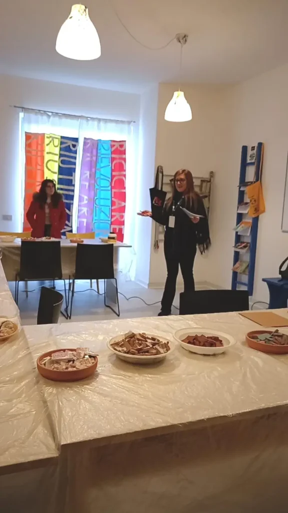 Operatrice introduce ai partecipanti materiali e attività di riuso creativo durante un laboratorio di ECOSCENA